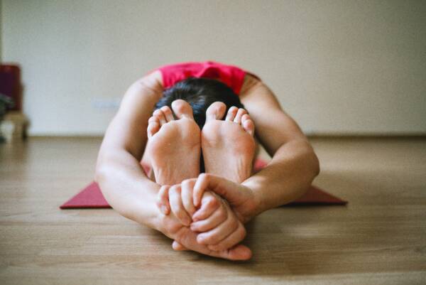 vrouw in yogahouding met armen rond de benen