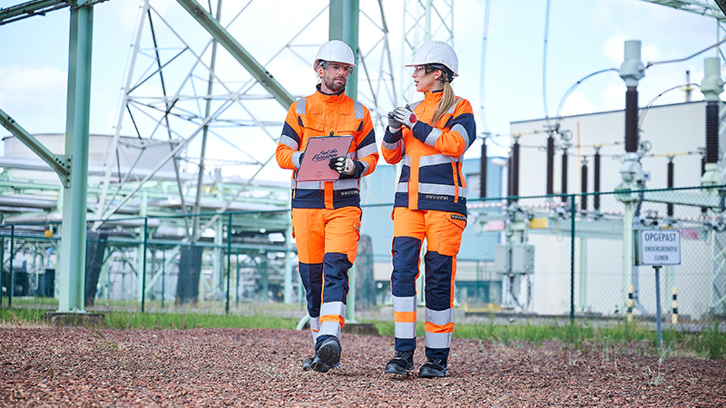 Werkman en werkvrouw op een industrieterrein in multinorm workwear uit de UP-collectie van Sioen