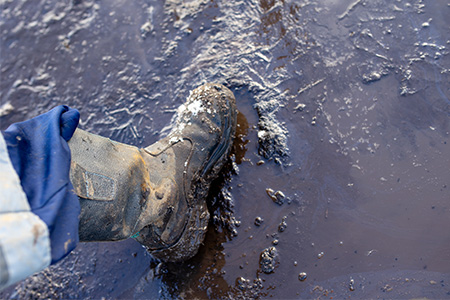 Work boots in mud in freezing conditions, as an example of harsh conditions in the workplace