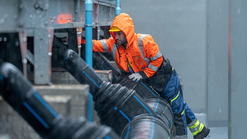 A workman in rainwear is working in the rain