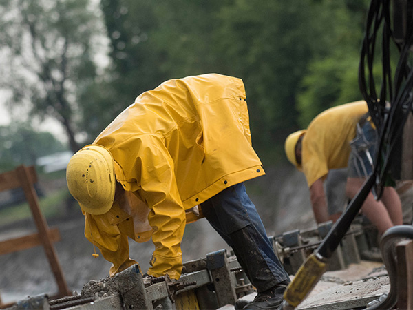 a workman in a yellow raincoat on a building site