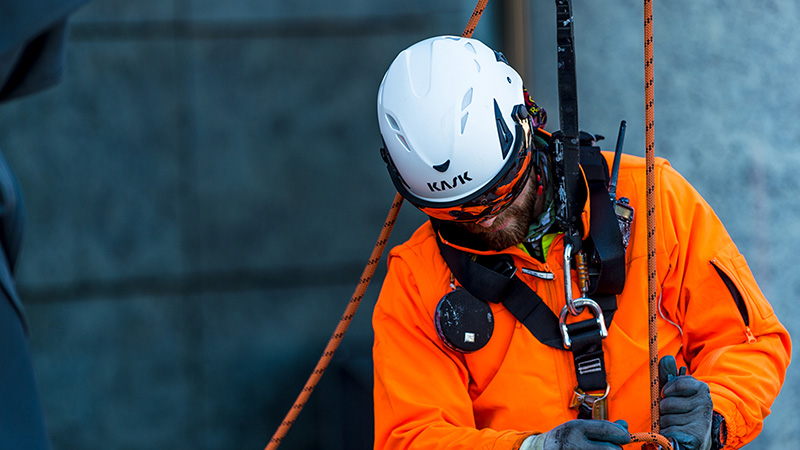 A workman is wearing a KASK safety helmet and a fall arrest harness